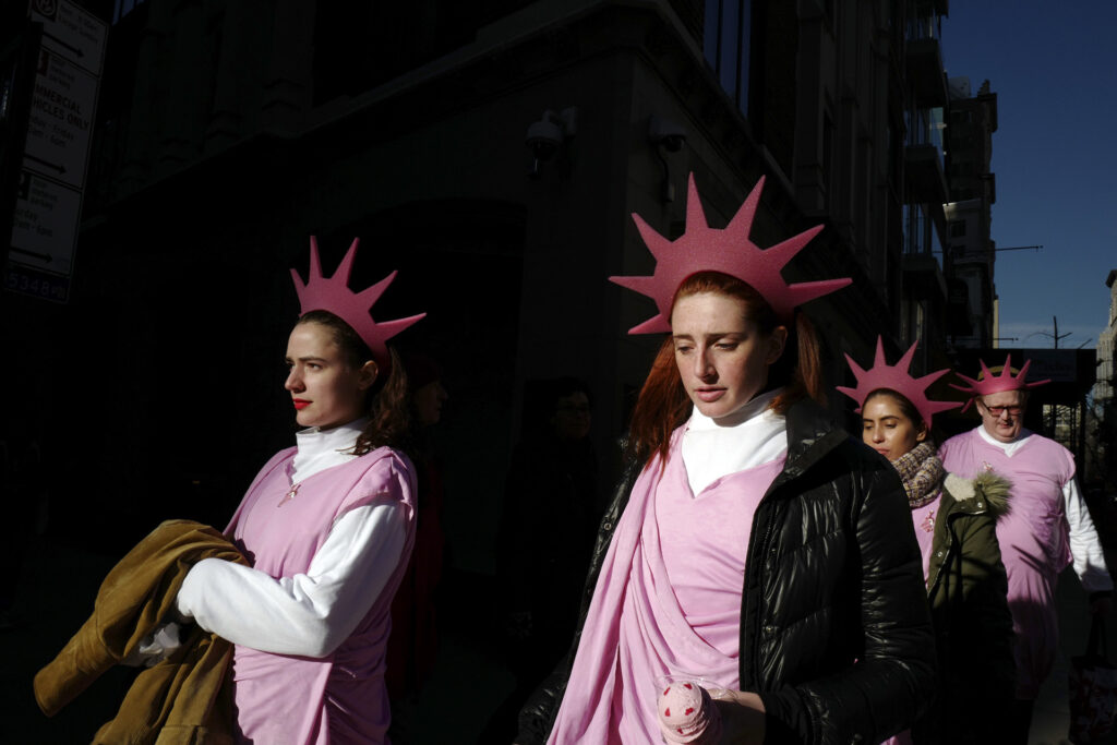 parade of people dressed as statue of liberty in pink