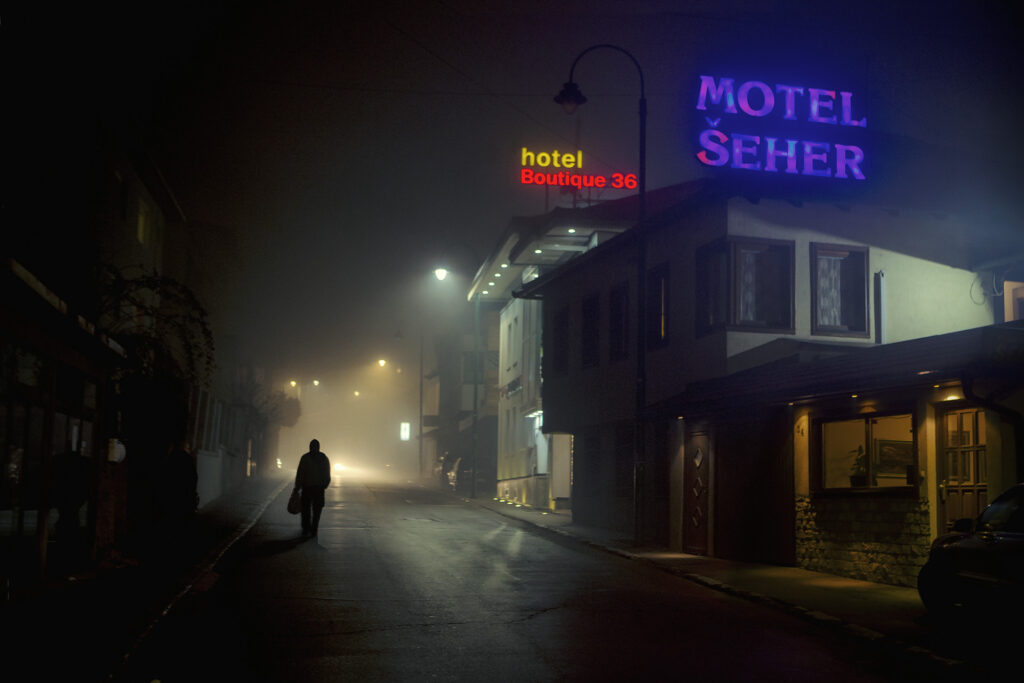 night street with hotel and motel neons and person walking alone
