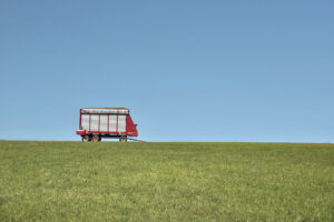 blue sky, green grass, a red trailer