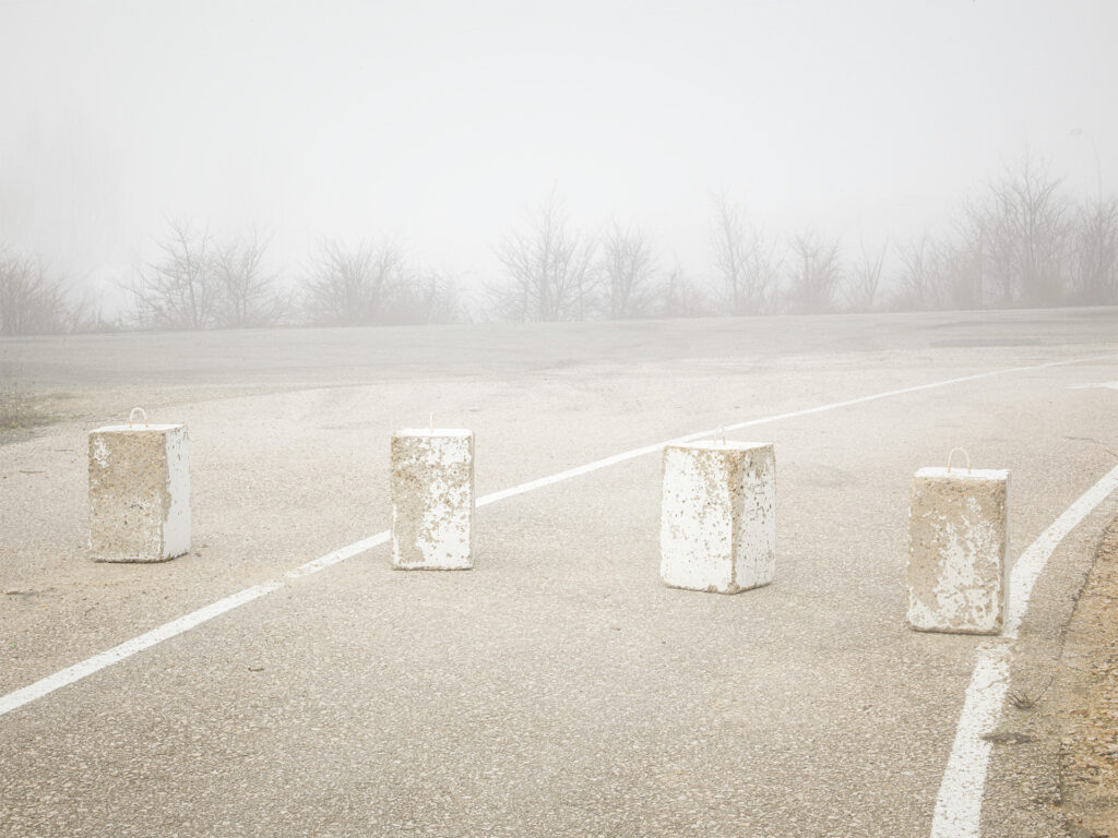 white cement blocks in the middle of a road on a foggy day