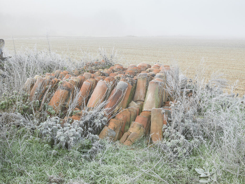 red roof tiles piled up in a field on a winter day